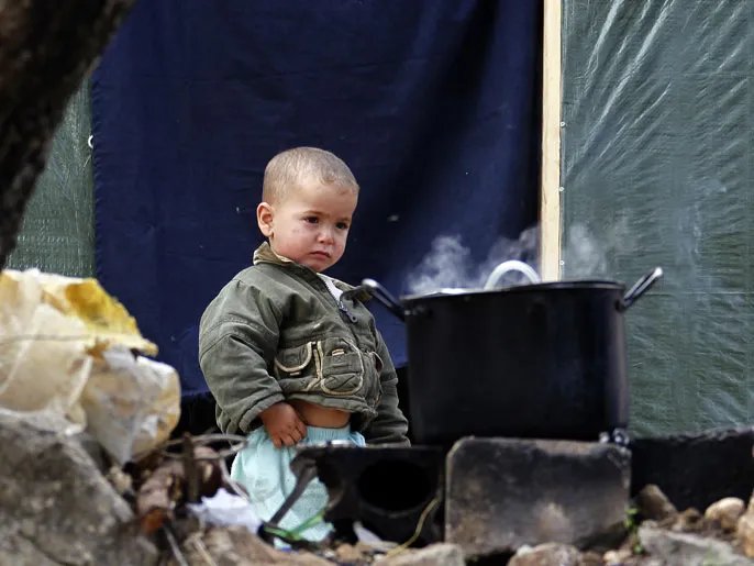 epa03966196 A Syrian refugee child stands next to a cooking pan at the Syrian refugee camp in Ketermaya village, near Sidon, southern Lebanon, 26 November 2013.